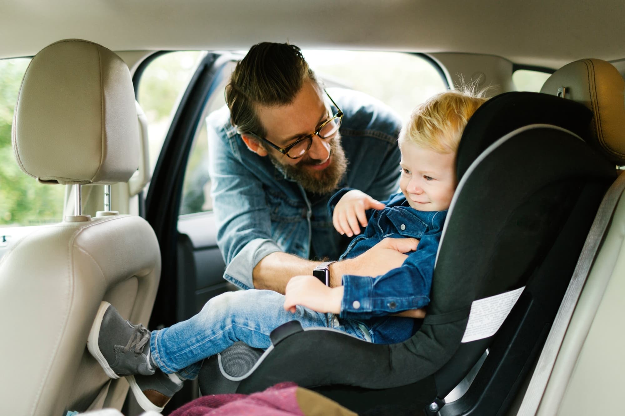 Dad putting a child in a car seat.